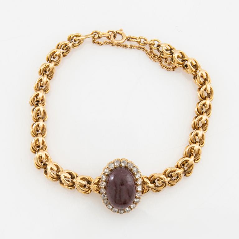 Bracelet in 18K gold set with rose-cut diamonds and an oval cabochon-cut garnet.
