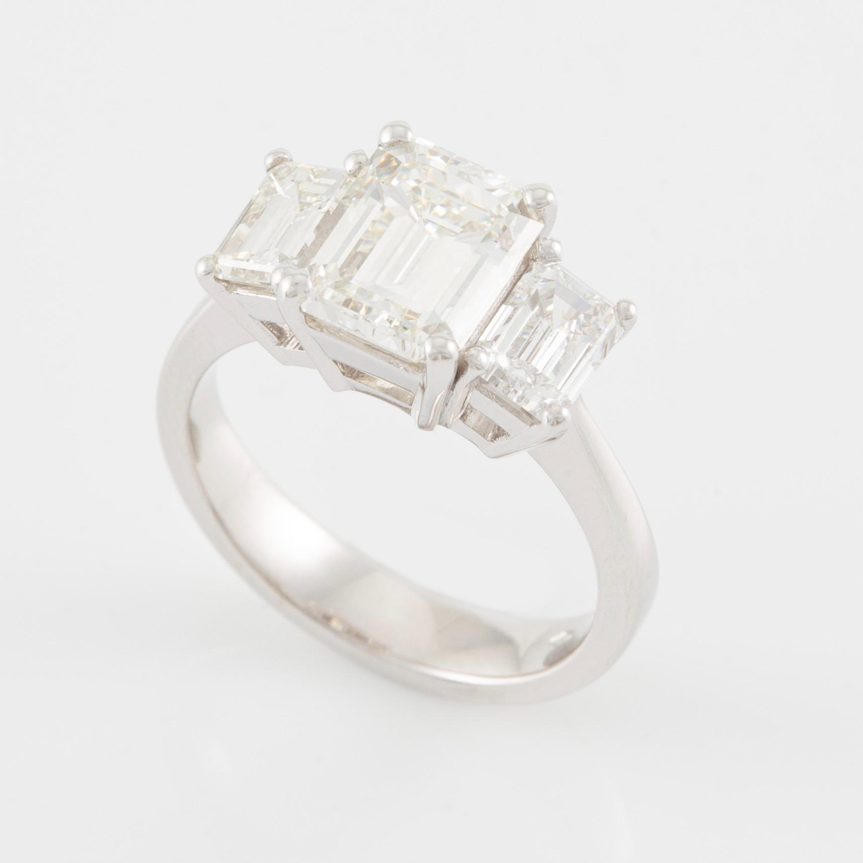 An 18K white gold ring set with three emerald-cut diamonds.