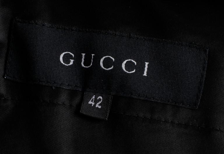 A two-piece black silk costume consisting of jacket and skirt by Gucci.