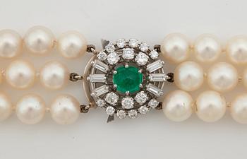 A three strand cultured pearl necklace, clasp with cabochon cut emerald circa 1.68 cts and diamonds.