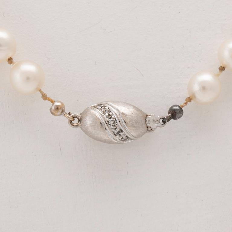 A necklace of cultured pearls with an 18K white gold lock set with single cut diamonds.