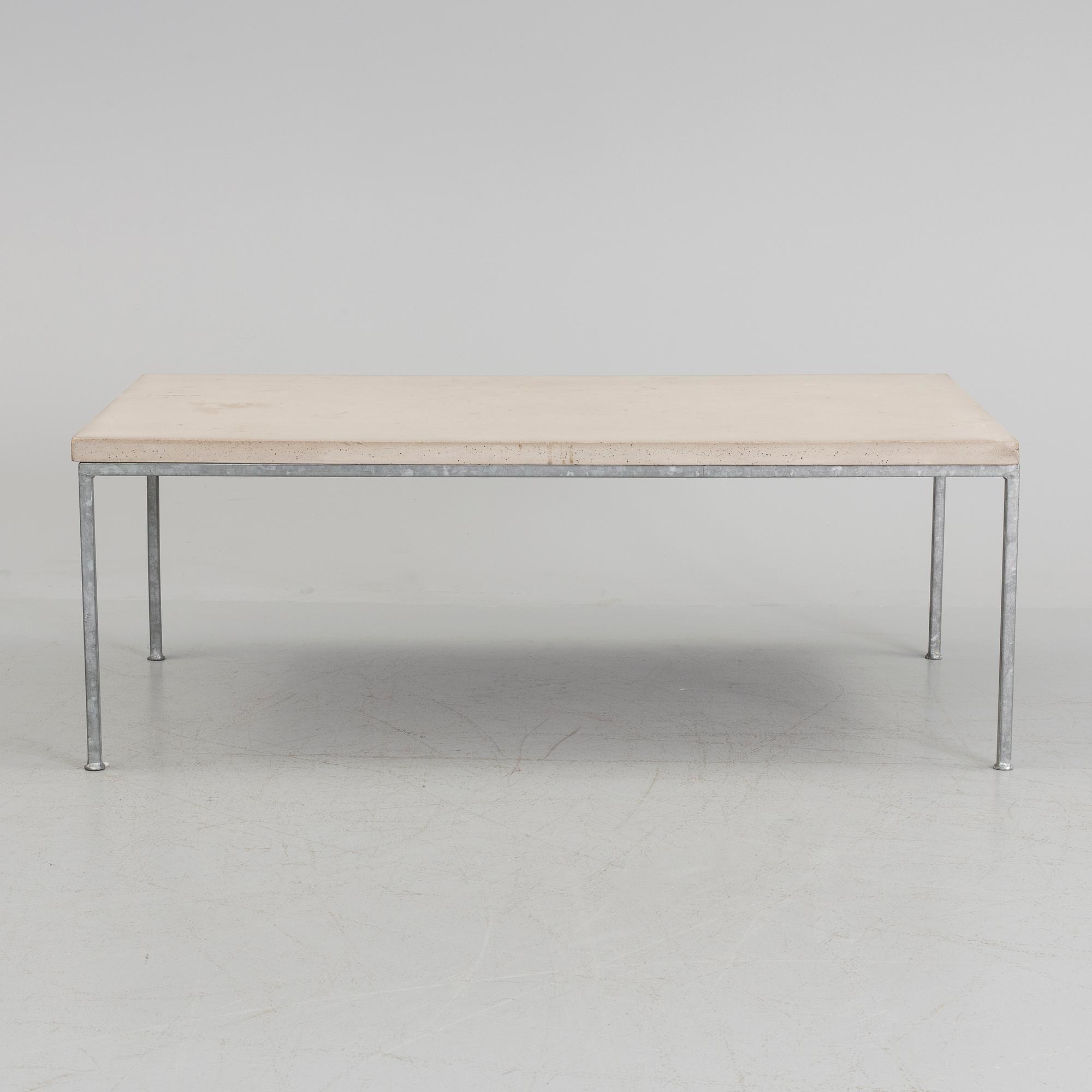 A modern sofa table with concrete top and steel legs.