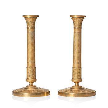 144. A pair of French Empire ormolu candlesticks, early 19th century.