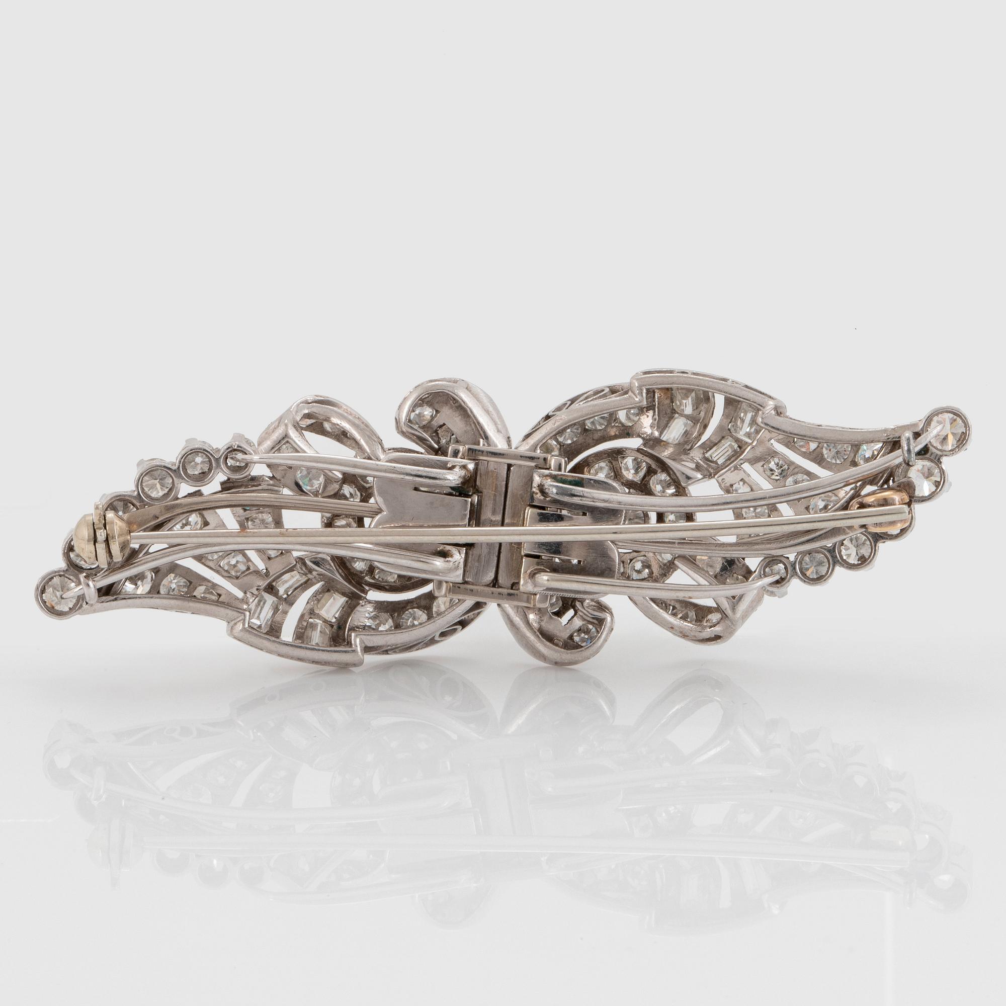 Dubbelclip/brosch platina med runda briljant-, smaragd- samt åttkantslipade diamanter.