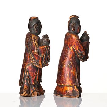 A pair of wooden gilt lacqer figures of officials carrying vases, 17/18th century.