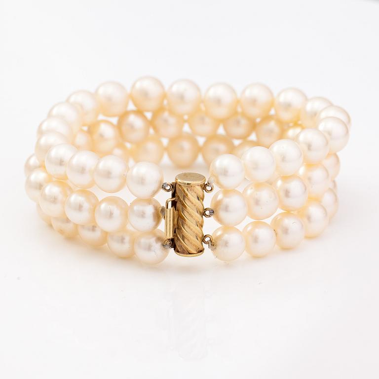 A three-strand pearl bracelet with cultured pearls and a 14K gold clasp.