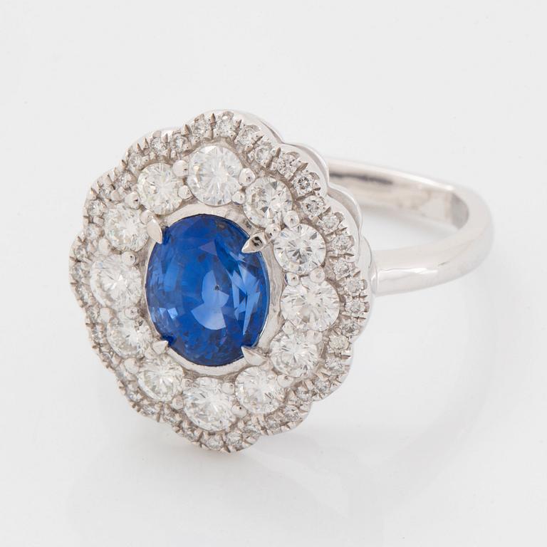 A platinum ring set with a faceted sapphire and round brilliant-cut diamonds.
