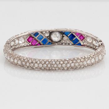 A platinum bangle set with old- and rose-cut diamonds and faceted sapphires and rubies.