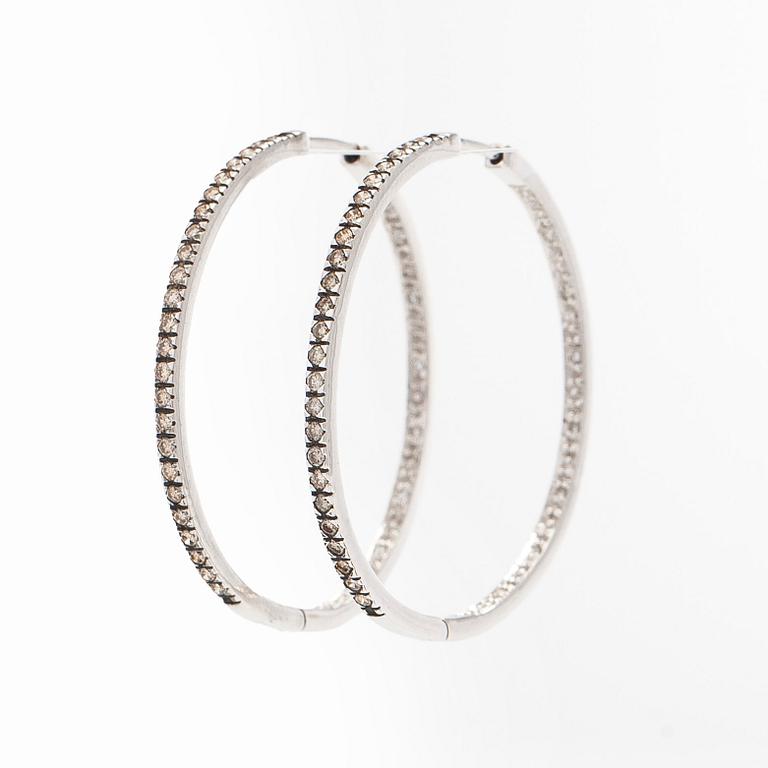 A pair of 14K white gold  hoop earrings with diamonds.