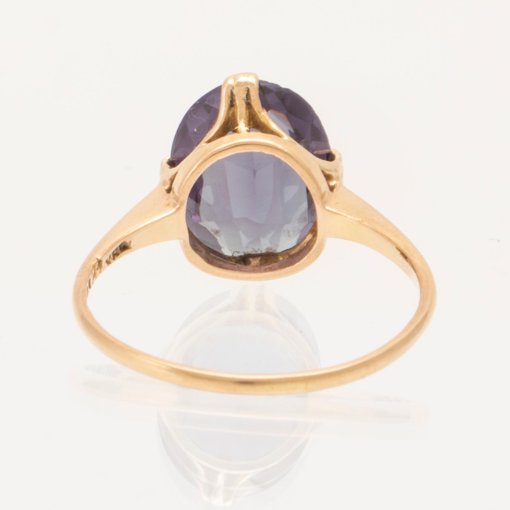 An 18K gold ring set with a synthetic colourchange purple sapphire.