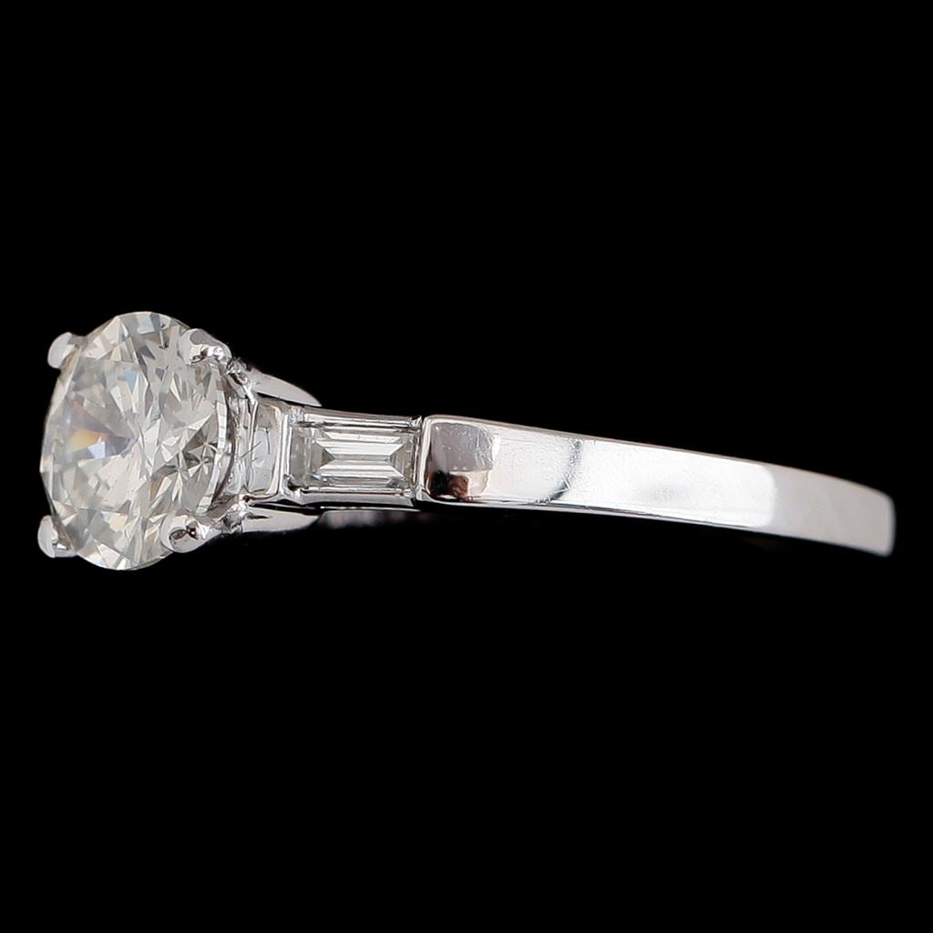 RING, 18 k vitguld, solitär briljantslipad diamant ca 1.00 ct, 2 baguetteslipade diamanter tot ca 0.16 ct.