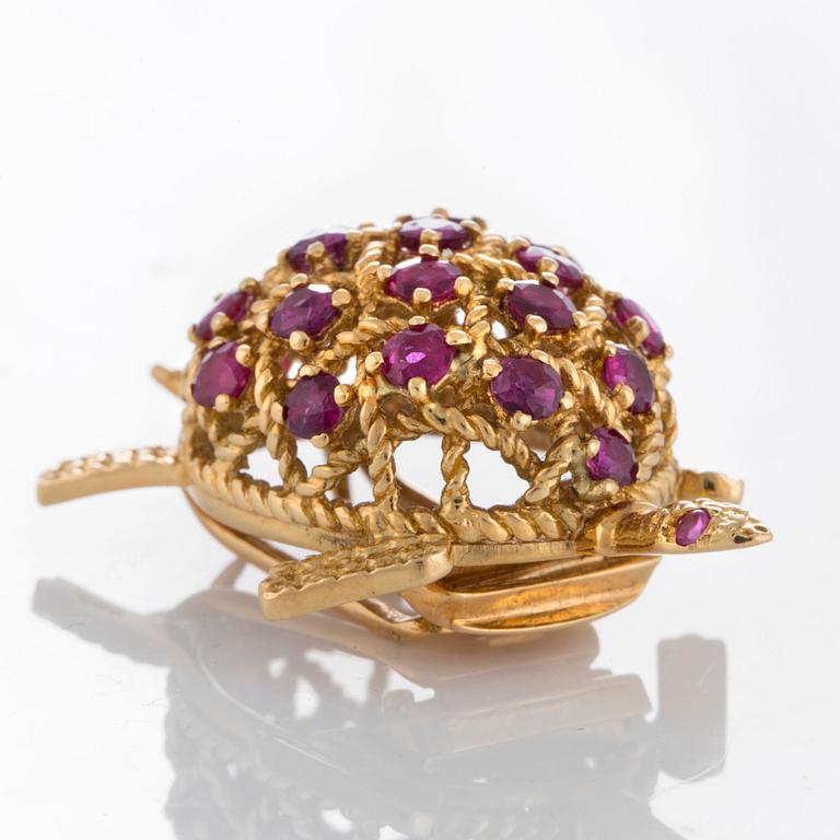 A Cartier turtle brooch in 18K gold set with rubies.