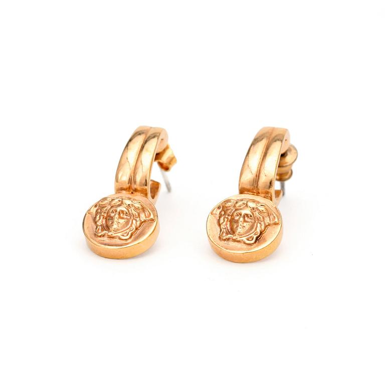VERSACE, a pair of gold colored earrings.