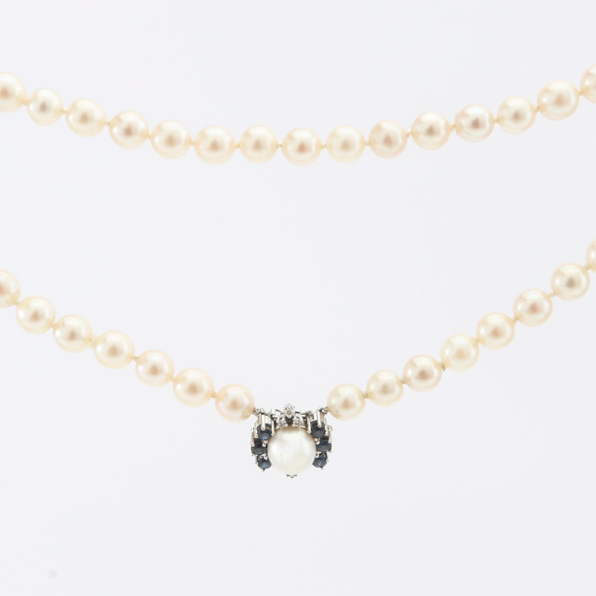 Halsband av odlade pärlor med lås 18K vitguld och runda enkelslipade diamanter samt runda fasetterade safirer.