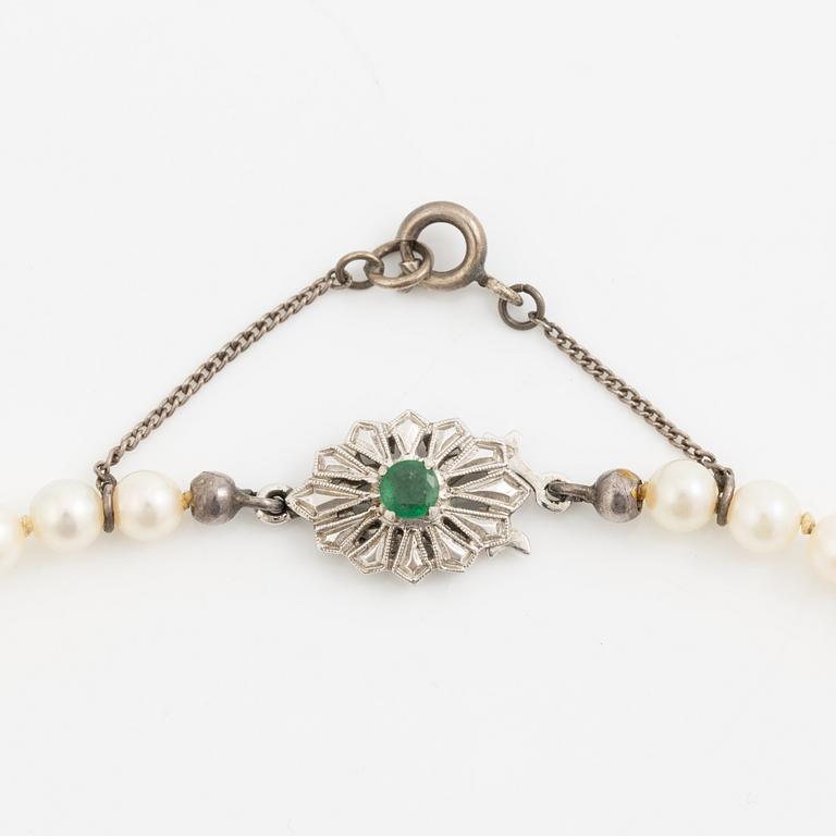Necklace with graduated cultured pearls, with a clasp in 18K white gold set with an emerald.