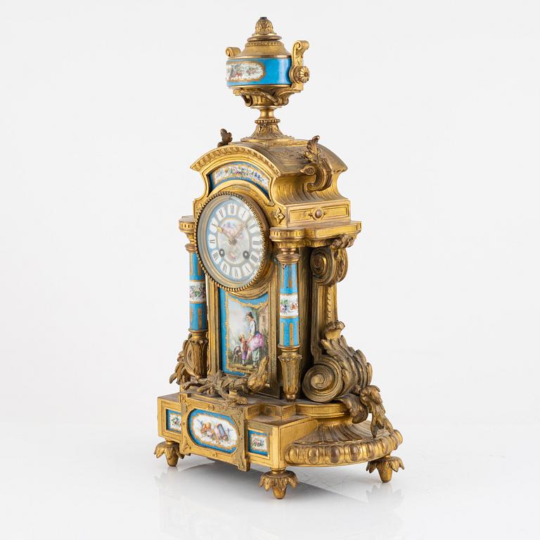 A French mantel clock, two urns and two depicters, second half of the 19th Century.