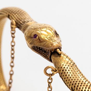 An 18K gold bracelet, in the form of a serpent, eyes set with a garnet and a syntethic ruby. Swedish import mark.