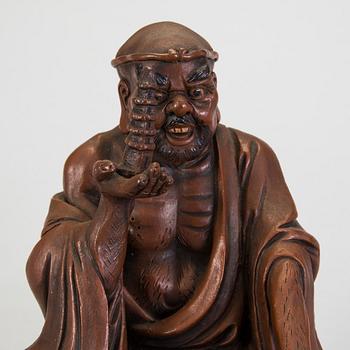 A Japanese earthenware seated figure of a man holding a pagoda, 20th century.