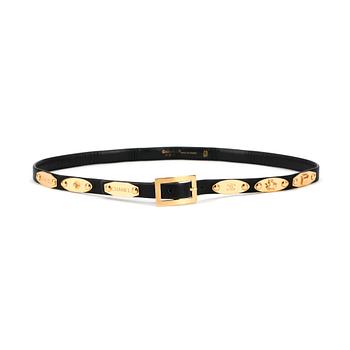 615. CHANEL, a skinny black leather belt with gold colored hardwear.