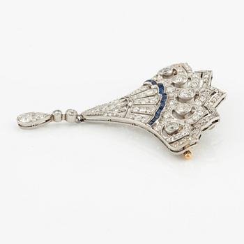 A platinum brooch with round brilliant, eight-, and rose-cut diamonds and calibré-cut sapphires.