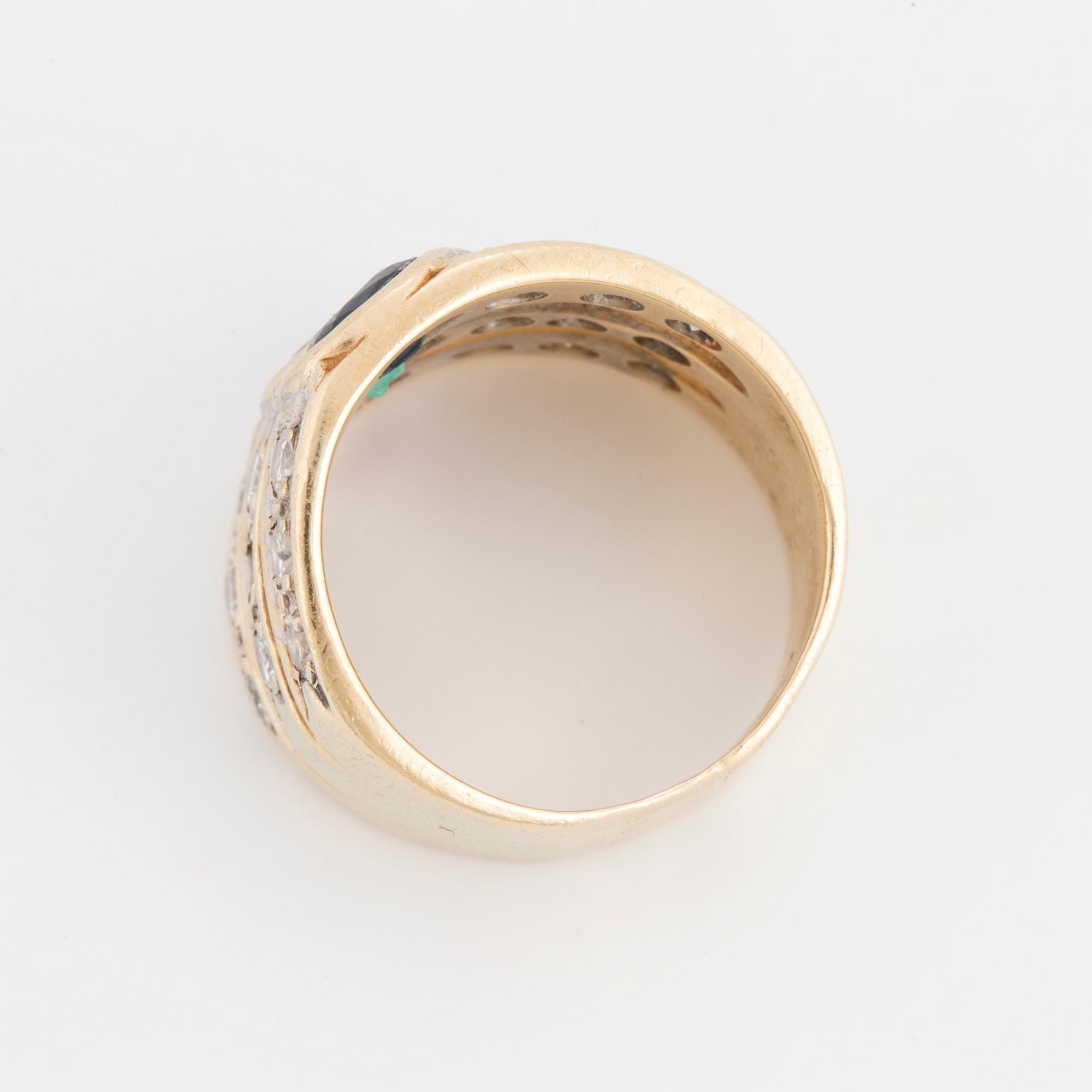 An oval cut ruby, sapphire and emerald ring, surrounded by brilliant cut diamonds.