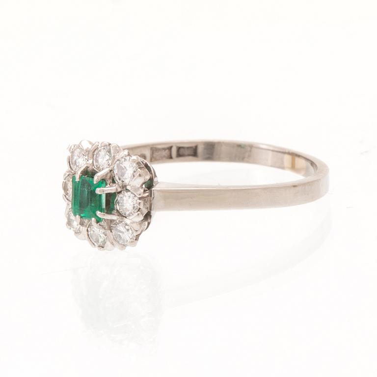 An 18K white gold ring set with a step cut emerald and round brilliant cut diamonds, Stockholm 1964.