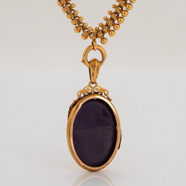 An 18K gold locket set with a pearl and an 18K gold chain.