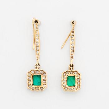 A pair of platinum and gold earrings set with step-cut emeralds and old-cut diamonds.