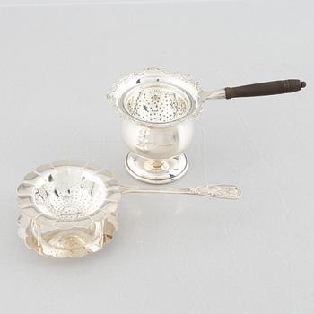 Two sterling silver tea strainers with stands, 20th century.