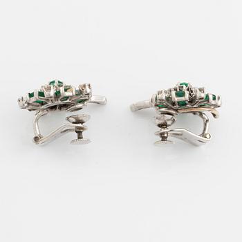 A pair of 14K white gold, emerald and round brilliant- and baguette cut diamond ear clips.