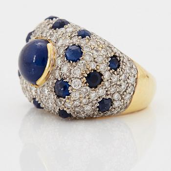 An 18K gold ring set with a cabochon-cut sapphire and round brilliant-cut diamonds and faceted sapphires.