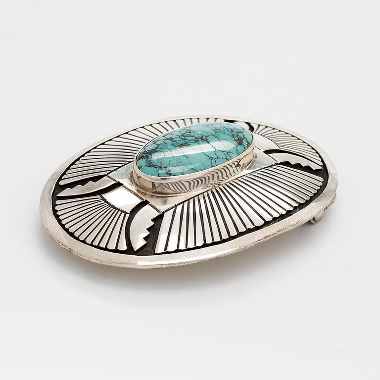 Chester Benally, a silver belt buckle with a turquoise, Navajo.