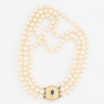 Pearl necklace, three strands of cultured pearls, with a clasp in 18K gold set with a sapphire and brilliant-cut diamonds.