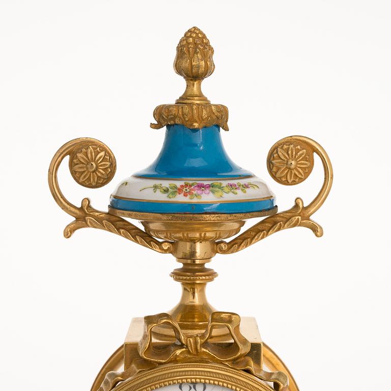 A mid-19th-century French gilt-brass mantel clock with a pair of candelabra by Dussault.