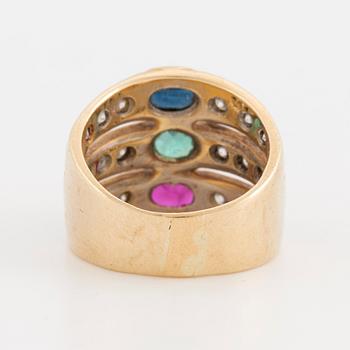 An oval cut ruby, sapphire and emerald ring, surrounded by brilliant cut diamonds.