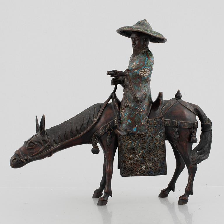 A Chinese bronze and cloissoné figurine on a mule, late Qing/early 20th century.