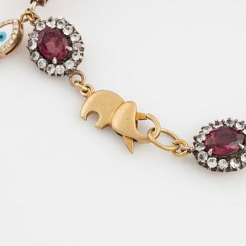 Bracelet with garnets and white stones, two charms, one eye enamel with brilliant cut diamonds, possibly oriental pearl.