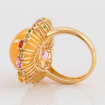 An 18K gold ring set with an opal, round brilliant-cut diamonds.