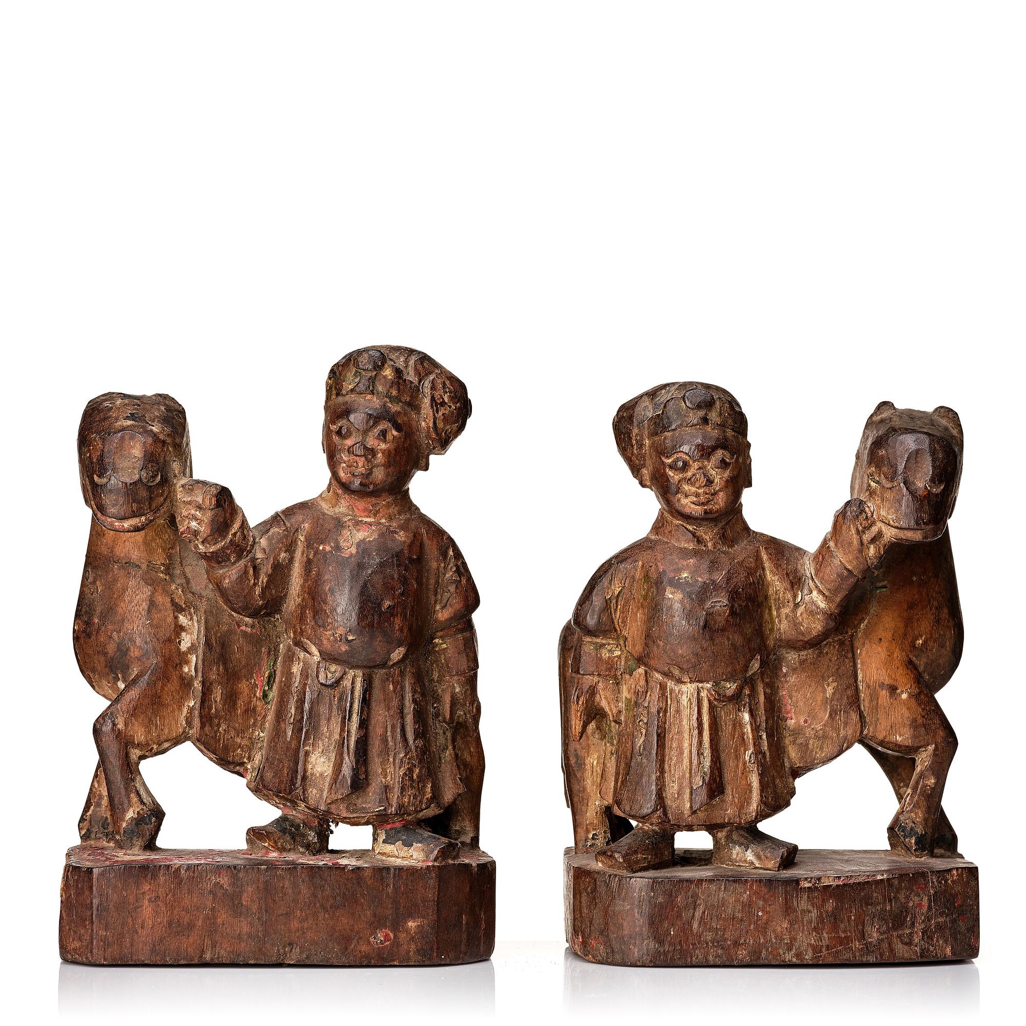A pair of wooden sculptures of a man with a horse, Qing dynasty, circa 1900.