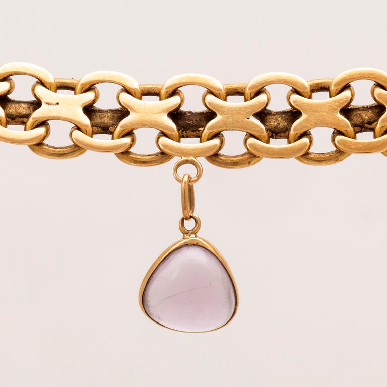 An 18K gold x-link bracelet with cabochon cut amethyst.