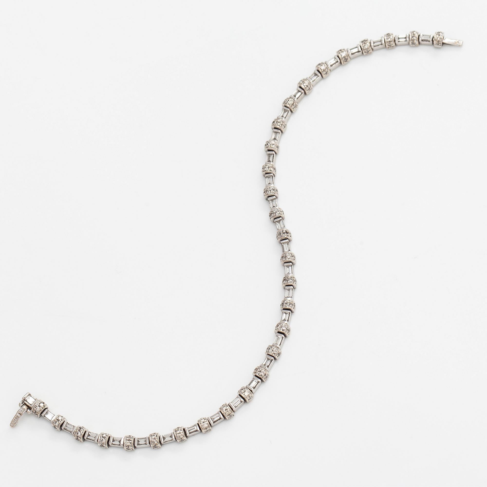 An 18K white gold bracelet set with baguette and brilliant-cut diamonds.