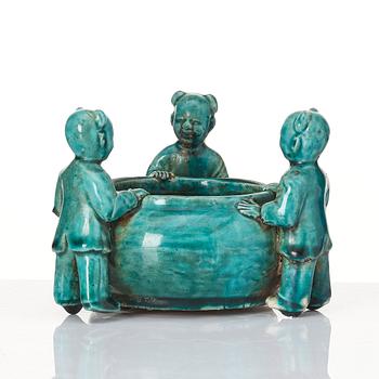 A turquoise glazed vessel supported by a group of boys, Qing dynasty, Kangxi (1662-1722).