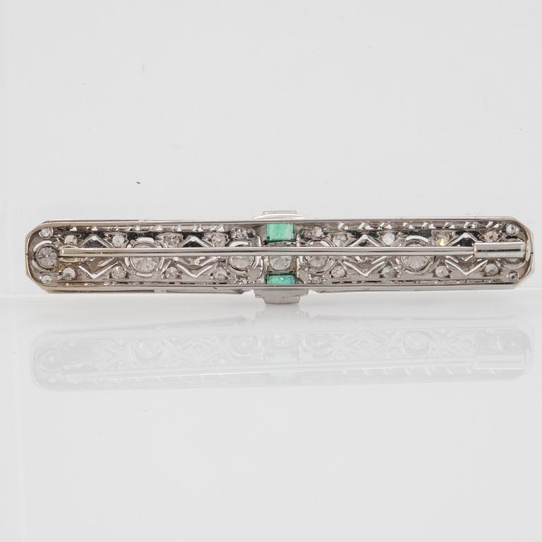 An 18K white gold brooch set with old- and eight-cut diamonds and faceted emeralds.