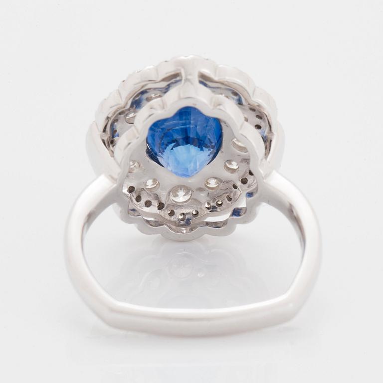 A platinum ring set with a faceted sapphire and round brilliant-cut diamonds.