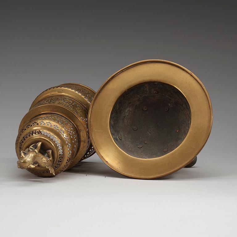 A four-part brass tripod censer, pierced sections with lotus scrolls and a fo-dog finial, late Qing dynasty (1644-1912).