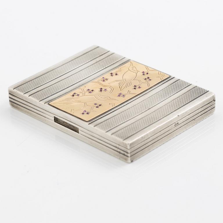 Puderdosa, silver samt guld. Med dekor av fåglar och rosa stenar.