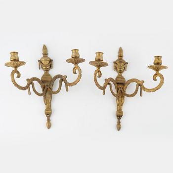 A pair of brass Louis XVI-style two-light wall lights, early 20th Century.
