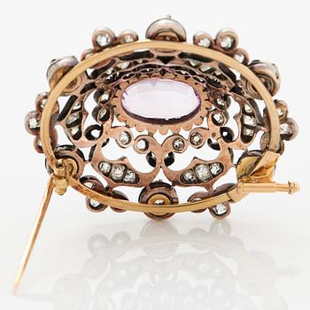 A 14K gold and silver brooch set with an oval faceted pink topaz and old- and rose-cut diamonds.