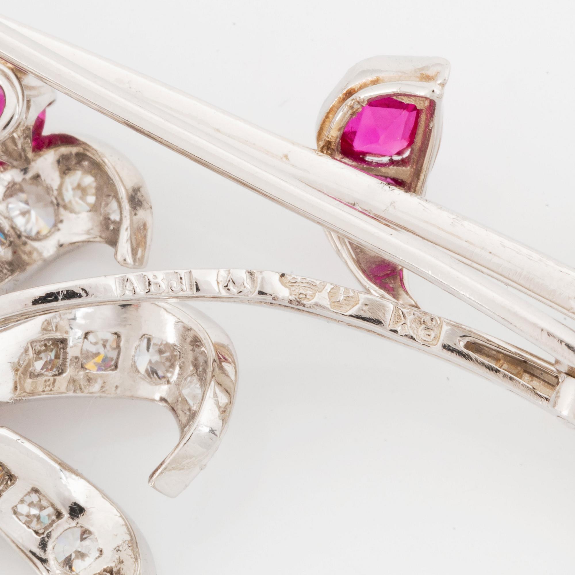 Brosch platina med fasettslipade rubiner och runda briljant- och åttkantslipade diamanter.