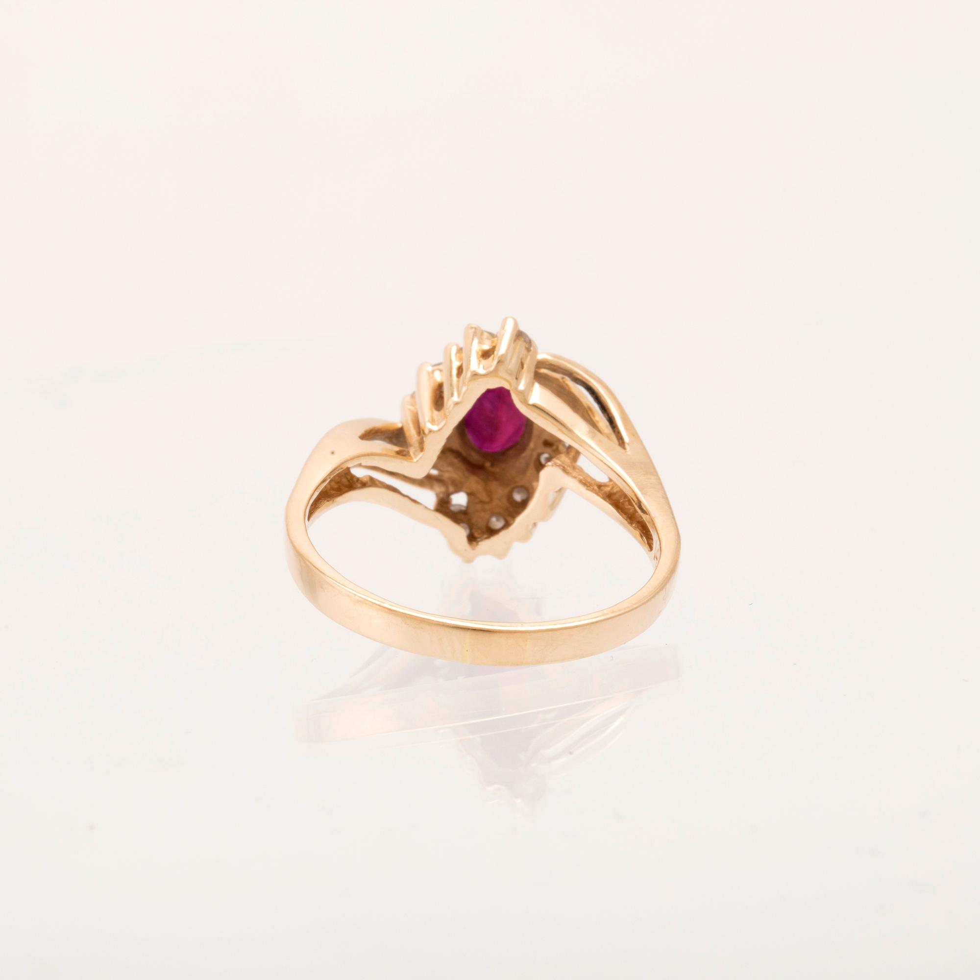 A 14K gold ring set with an oval faceted synthetic ruby and round brilliant-cut diamonds.